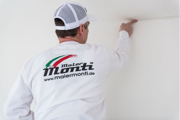 Mitarbeiter von Maler Monti bei der Qualitätskontrolle an einer frisch gestrichenen Innenwand