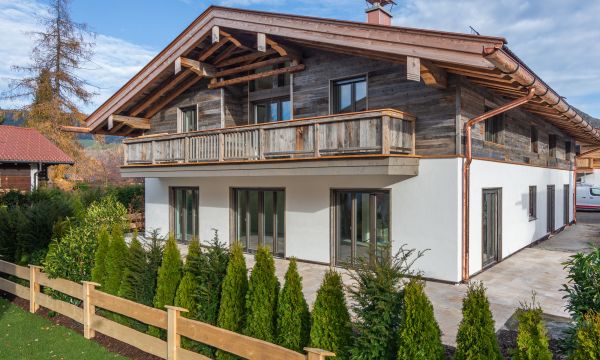 Außenansicht eines alpenländischen Neubaus am Tegernsee mit weißem Anstrich von Maler Monti und Altholzelementen