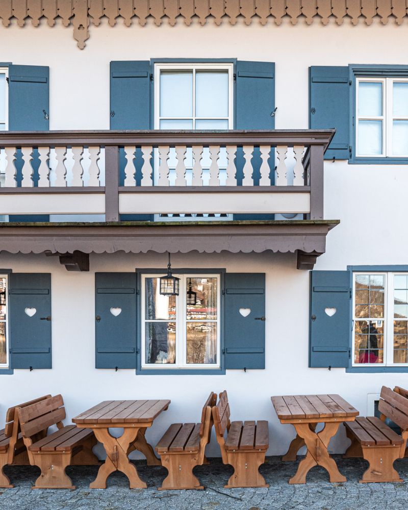Außenansicht eines von Maler Monti frisch gestrichenen Gasthauses mit blauen Fensterläden am Tegernsee