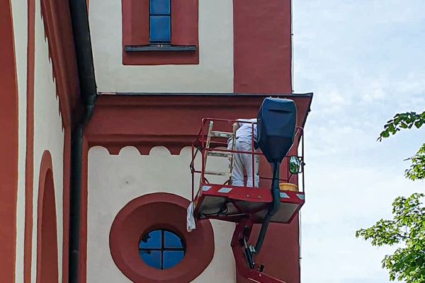 Malerarbeiter der Firma Maler Monti an der Fassade einer Kirche am Tegernsee
