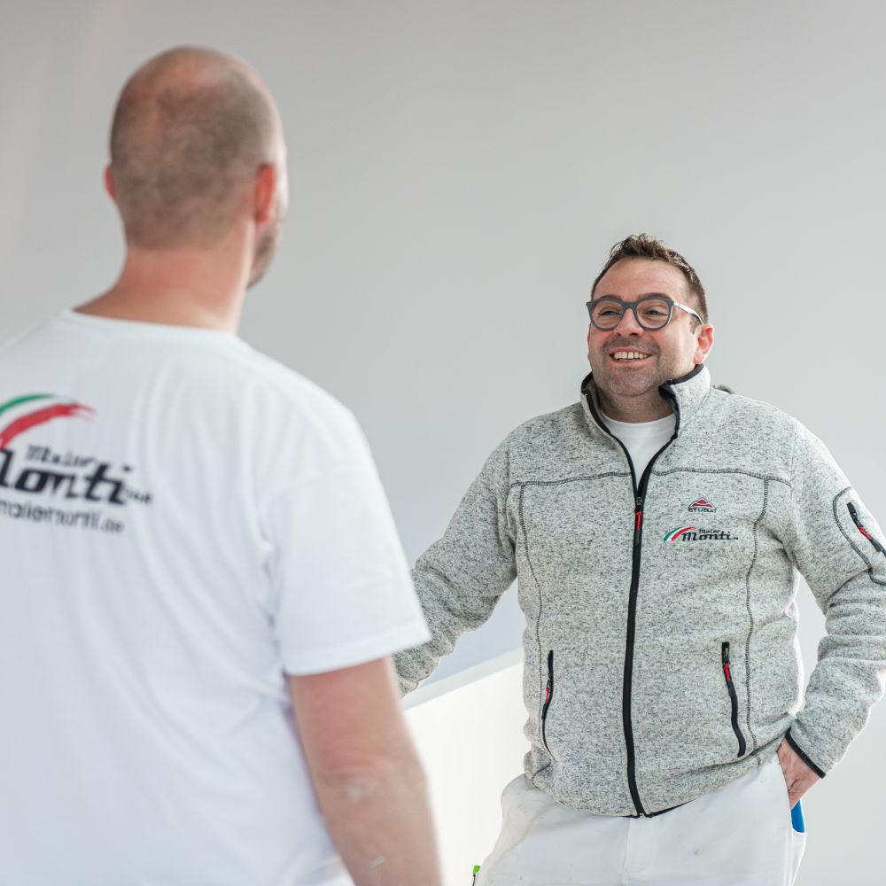 Inhaber Andrea Monti im Gespräch mit Mitarbeiter auf einer Baustelle eines Neubaus am Tegernsee