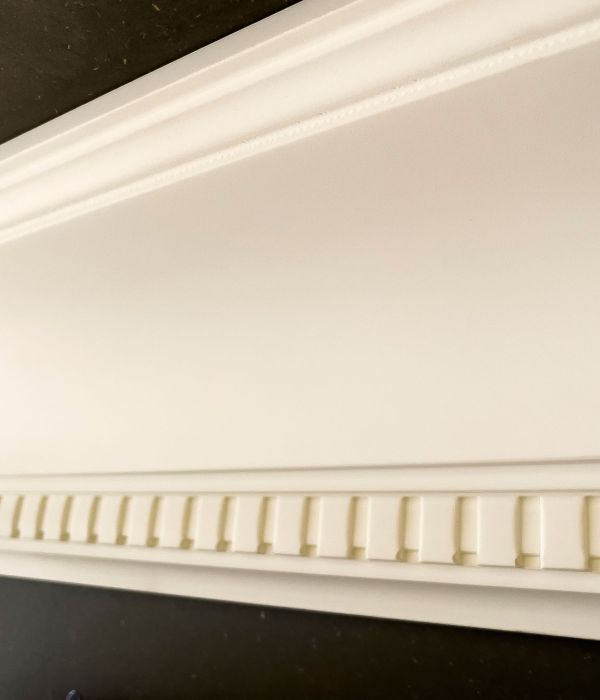 Aufwändige weiße Zierleiste von Maler Monti setzt optischen Akzent auf dunkler Wand am Tegernsee