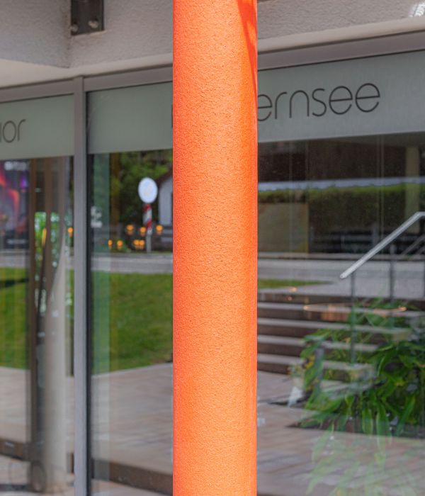 Feuerhemmender Anstich in Orange an einer Stahlsäule als Blickfang an einem Geschäftshaus in Gmund