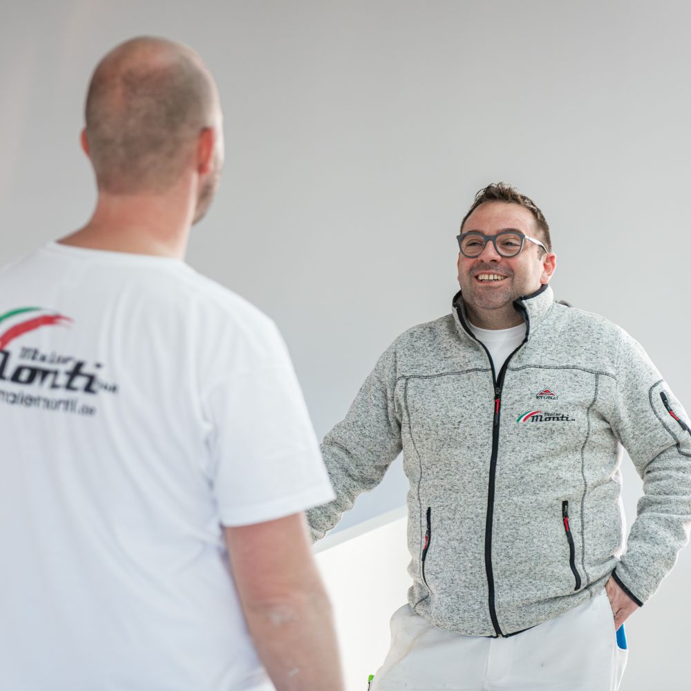 Inhaber Andrea Monti im Gespräch mit Mitarbeiter auf einer Baustelle eines Neubaus am Tegernsee